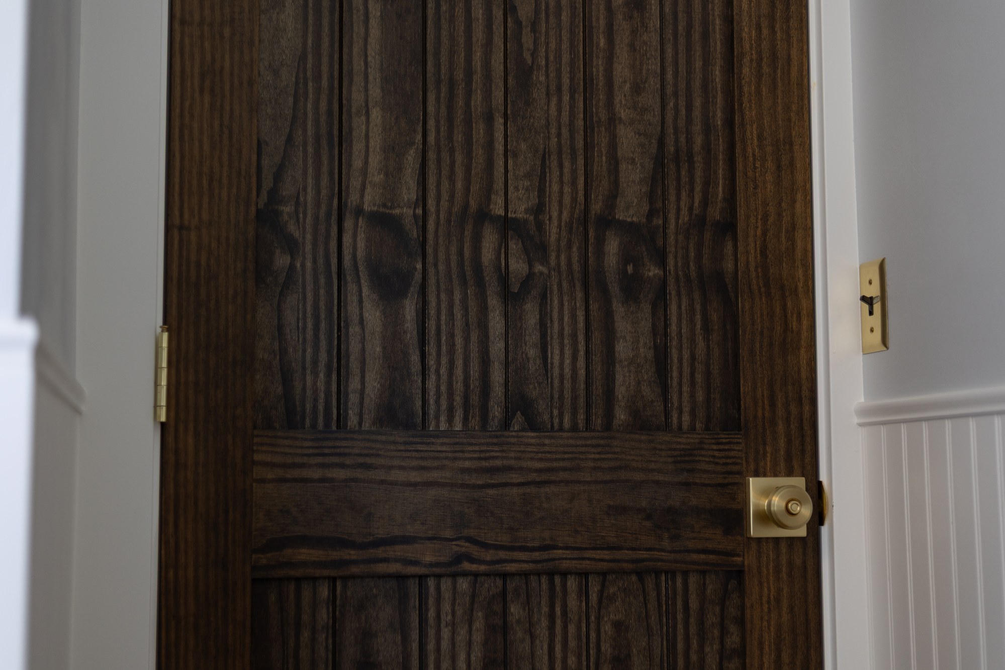Close-up of a dark-stained interior door with brass hardware
