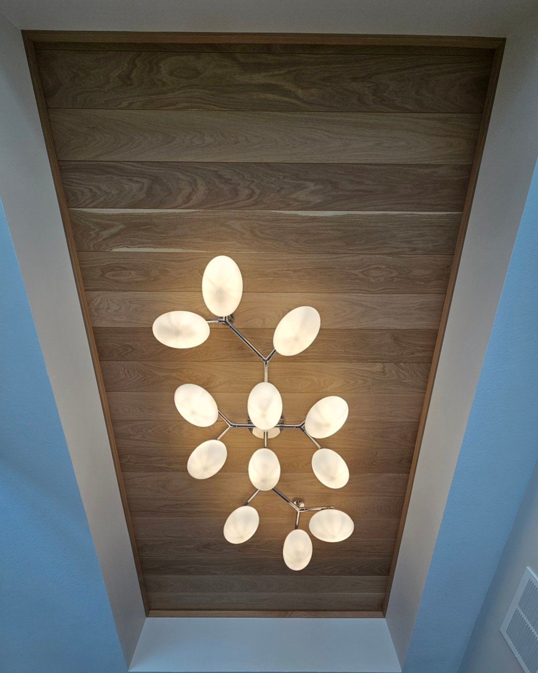 Custom wood-clad ceiling tray with sculptural light fixture