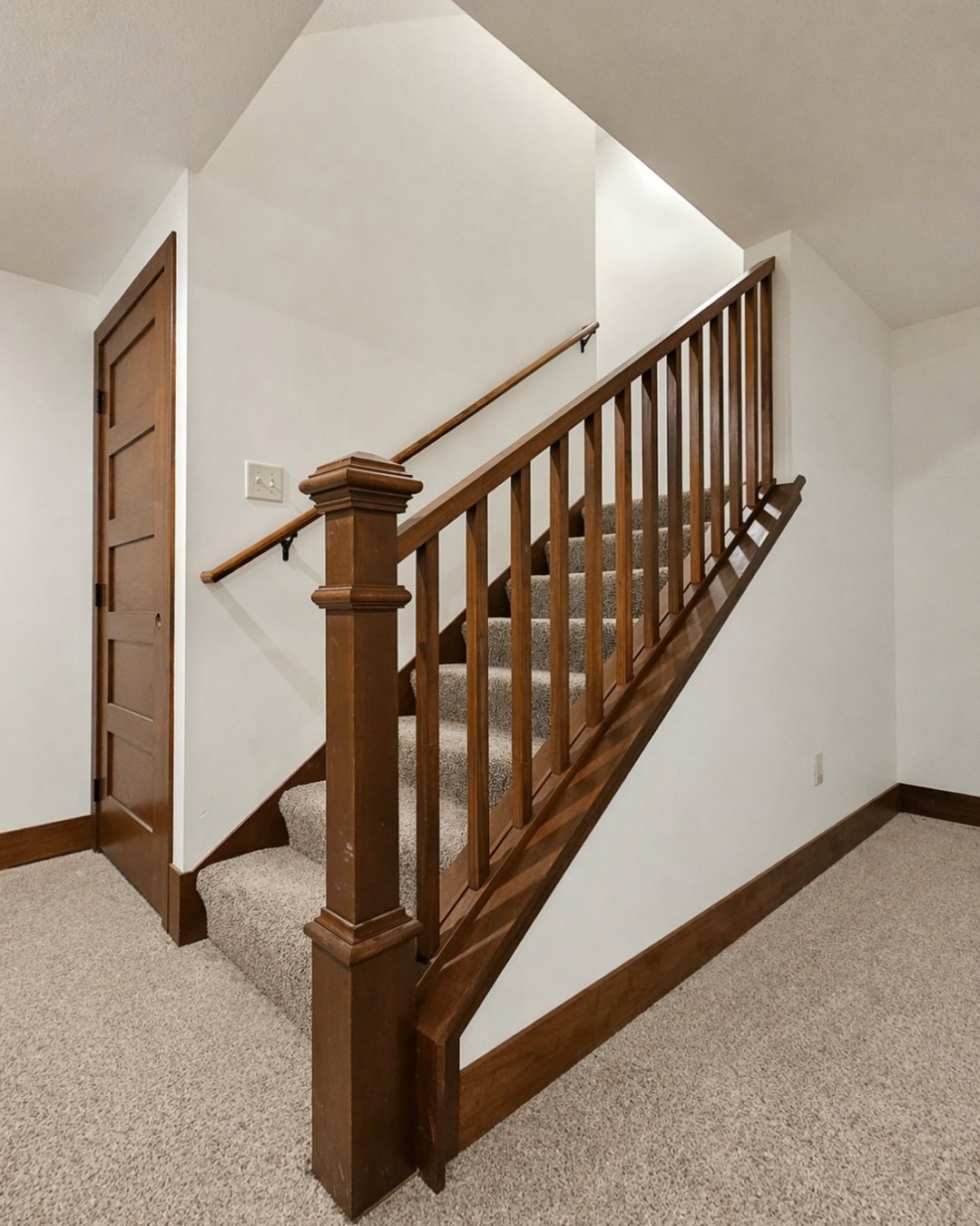 Stained wood staircase with newel post, balusters, and handrail